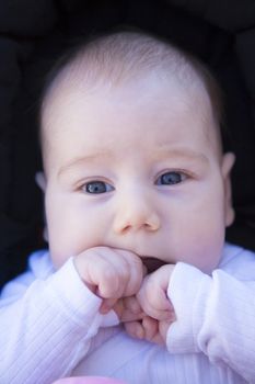three month baby with white dress looking at camera in woman arms outdoor