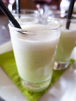 macro of short crystal glass full of green mojito typical cuban drink with black straw