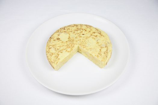 white dish with yellow spanish potato omelette on grey tablecloth