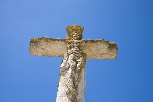 ancient white stone crucifix with Jesus in blue sky