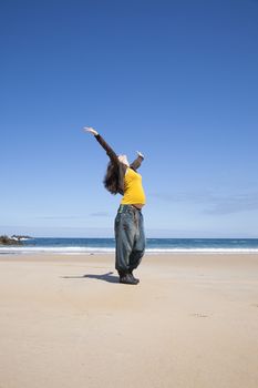 arms up pregnant woman with yellow shirt at Asturian beach