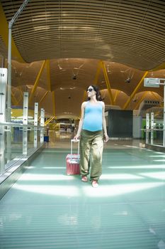 woman pregnant walking inside airport hall