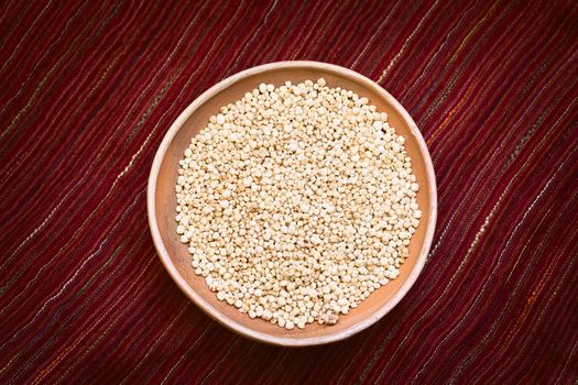 Overhead shot of popped white quinoa (lat. Chenopodium quinoa) cereal in bowl on red textile photographed with natural light 