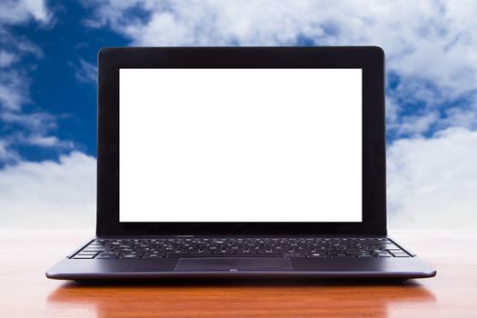 Tablet laptop with white blank screen on wooden table, front view, cloudy sky background.