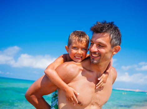 Father holding son on his shoulders at the beach