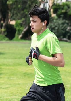 Young man at a local green park jogging (vertical)