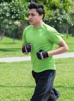 Young man at a local green park jogging (vertical)