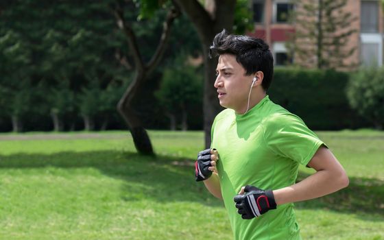 Young man at a local green park jogging 