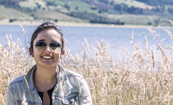 Young latin woman into a golden grass field smiling