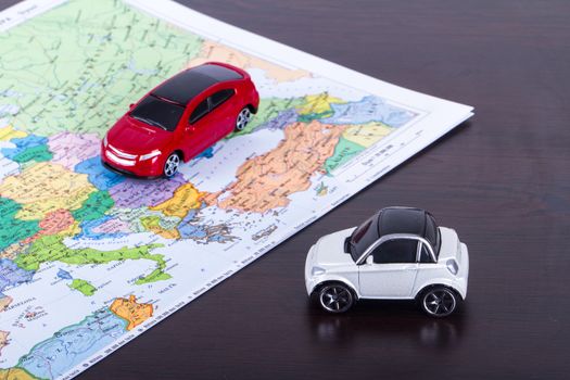 Small, toy car for travel concept on colorful map.