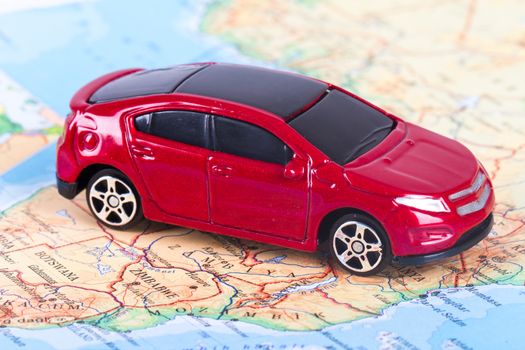 Side view of red, toy, small car on colorful map.