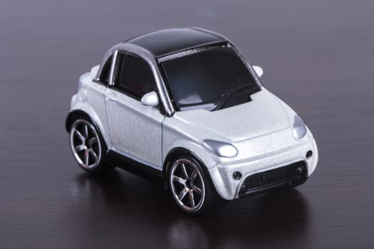 Side view of white, toy, small car on wooden table.