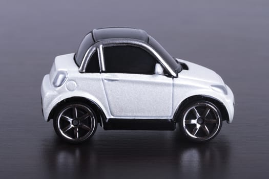 Side view of white, toy, small car on wooden table.