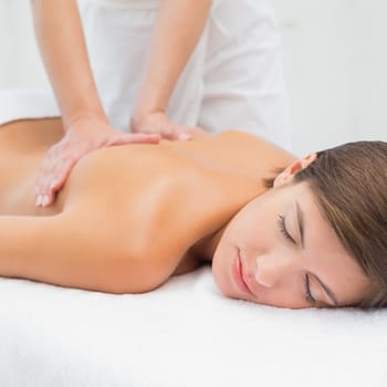 Close up of an attractive young woman receiving back massage at spa center