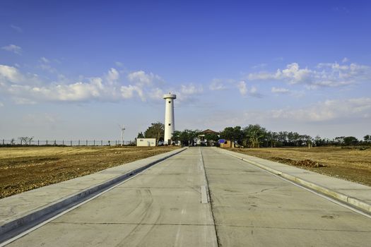 Newly built concrete road leading to a lighthouse undergoing restoration