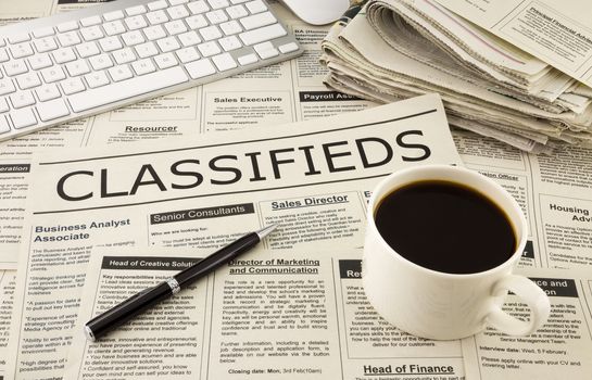 fake newspaper display classifieds advertising place on table with keyboard, pen and a cup of coffee