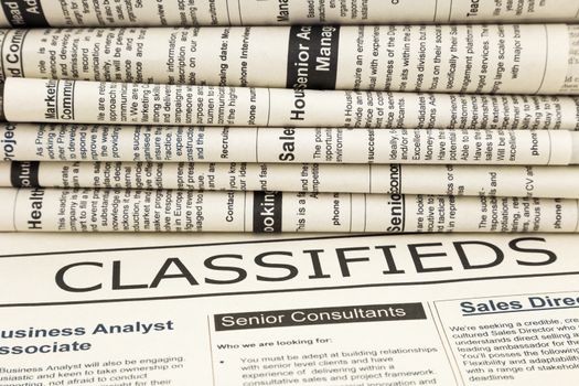 close up stack of fake newspapers, focus on classifieds word