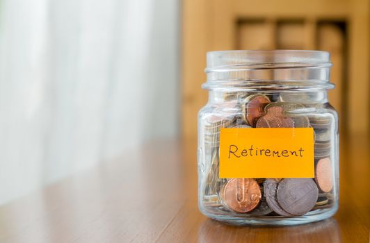 World coins in glass savings jar with retirement plan label