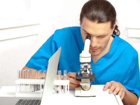 Male researcher looking through the microscope in the lab