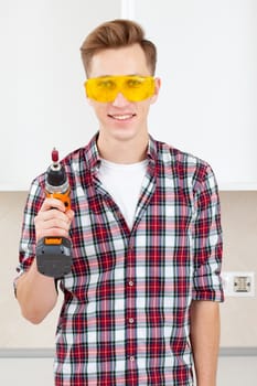 smiling builder in eyeglasses and with a drill in his hands