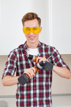 Worker holding electric drill and scredriver in safety eyeglasses