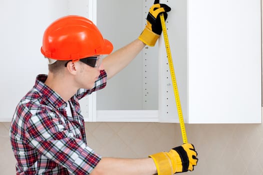 worker in a red protective helmet with a tape measure