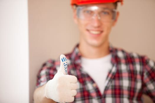 builder in a protective hardhat and gloves giving a thumbs up, focus on the hand