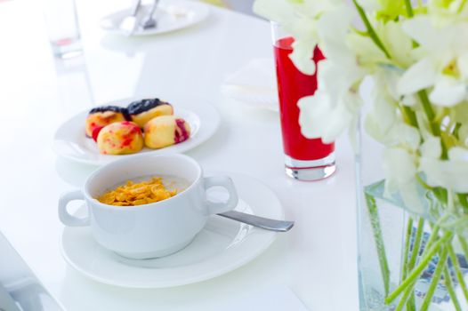 breakfast porridge in white cup, donuts and cranberry juice