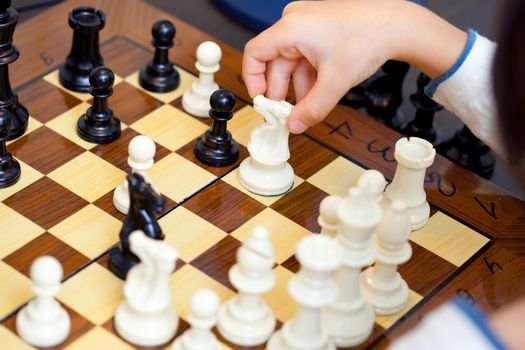 the child's hand with chess pieces on the board