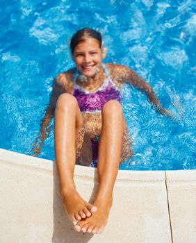 Cute happy young girl swimming and snorking in the swimming pool. Focus on the legs,