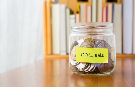 Many world coins in saving money jar with college label on jar, concept to financial planning for kids