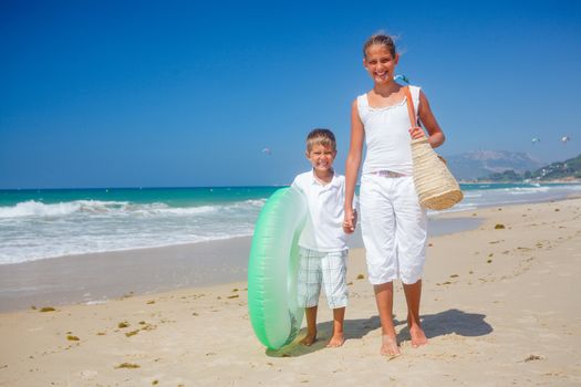 Beautiful brother and sister walk on the beach