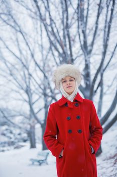 Happy teenager girl in fur hat walking in winter park