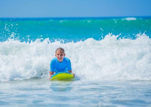 Teenage girl in blue has fun surfing