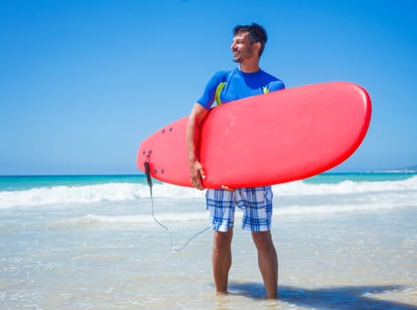 Strong young surf man at the beach with a surfboard.