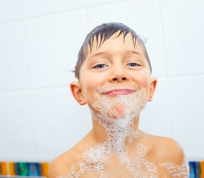 Close-up portrait of cute little boy in bathroom with foam