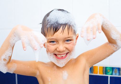 Portrait of cute little boy in bathroom with foam