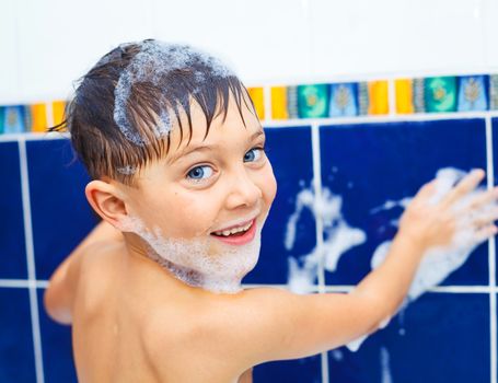 Portrait of cute little boy in bathroom with foam