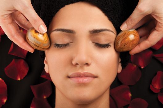 Facial massage with special marble eggs of a young woman.
