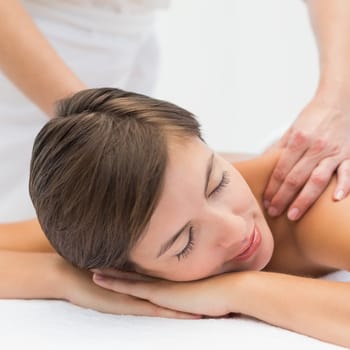 Close up of an attractive young woman receiving shoulder massage at spa center