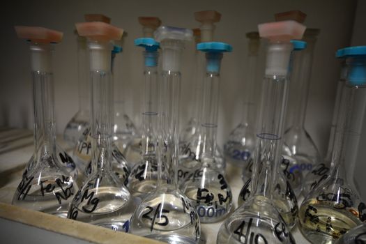 Laboratory glassware, grouped together half filled with various solutions chemical solutions.