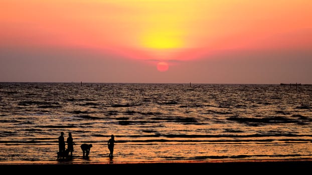 Silhouette people walking in sea with sunset sky, Bangsaen, Chonburi, Thailand