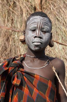 JINKA, ETHIOPIA - NOVEMBER 21, 2014: Young Mursi boy with traditional paintings on November 21, 2014 in Jinka, Ethiopia.