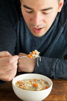 Man eating a hot bowl of fresh homemade chicken soup.