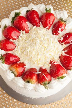 Top view of an entire strawberry shortcake with white chocolate shavings.