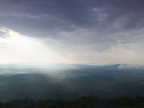 Sunlight shines through the clouds into the mountains and forests. Mist-covered mountains and trees.