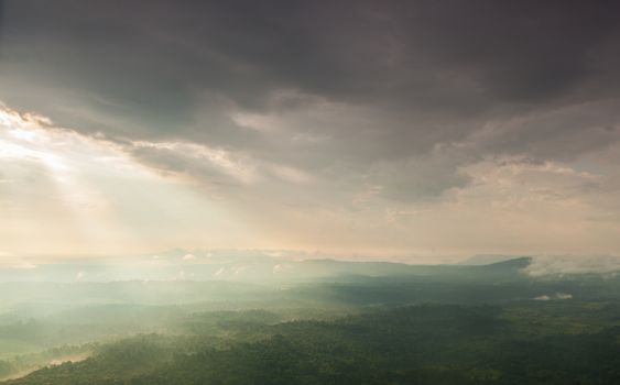 Sunlight shines through the clouds into the mountains and forests. Mist-covered mountains and trees.