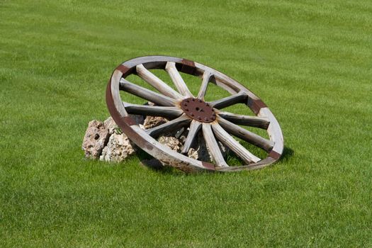 Old wooden wheel on grass.