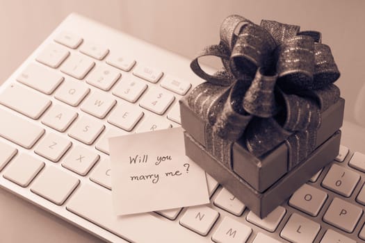 Gift box and paper note with romantic love message: Will you marry me? place on keyboard, valentine's day concept, Sepia toned