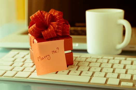 Gift box and sticky note with romantic love message: Will you marry me? place on keyboard, valentine's day concept, retro image style